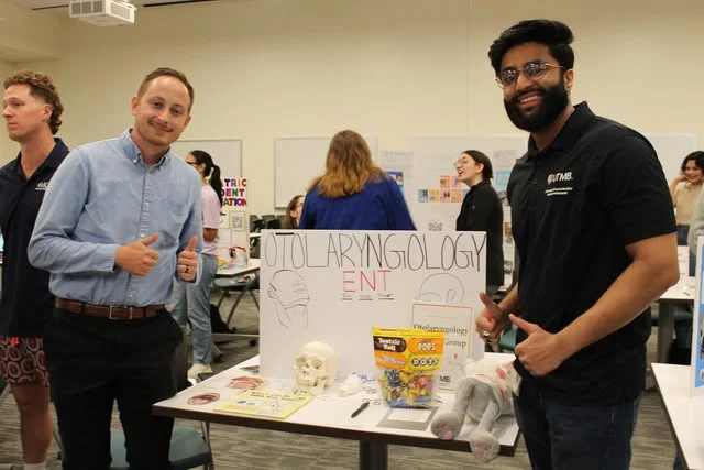 Students at the OIG table with an otolaryngology poster